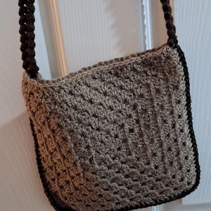 May include: A brown crocheted crossbody bag with a black crocheted strap.