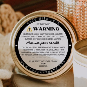 May include: A white candle tin with a black label that says "Made with Love" and has a warning about candle safety. The label also includes instructions on how to use the candle and the company's website address.