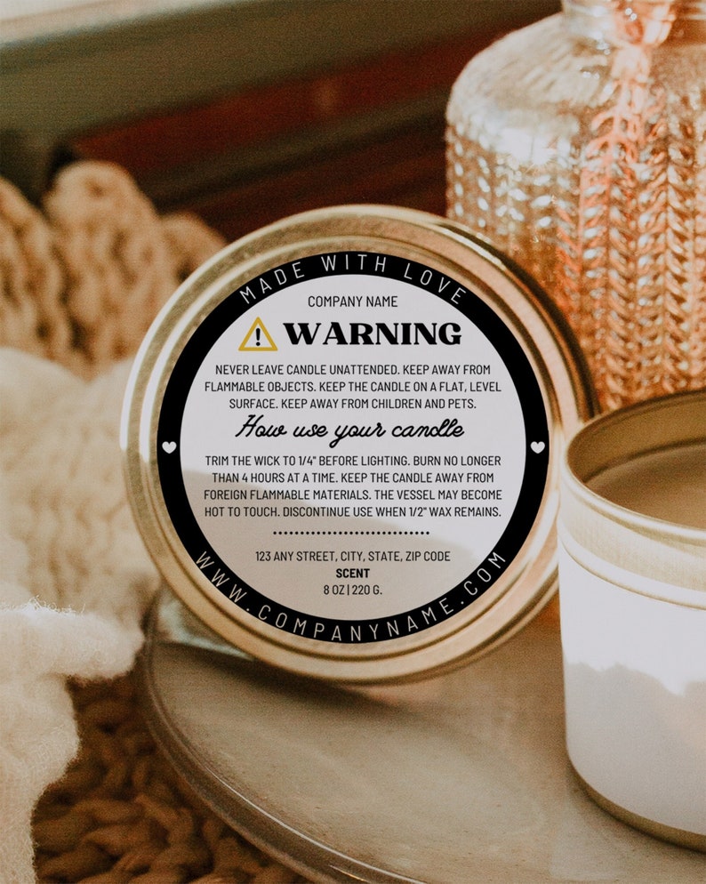 May include: A white candle tin with a black label that says "Made with Love" and has a warning about candle safety. The label also includes instructions on how to use the candle and the company's website address.