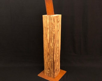 May include: A tall, rustic wooden pedestal with a rectangular metal base and top. The wood has a natural, weathered finish with a light brown colour. The metal base and top are a rusty brown colour.