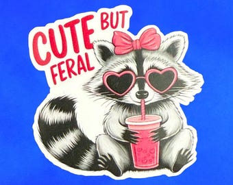Puede incluir: Una pegatina con un mapache con gafas de sol en forma de corazón y un lazo rosa. El mapache sostiene una bebida rosa con una pajita. El texto "CUTE BUT FERAL" está encima.