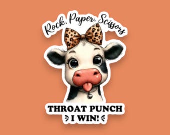May include: A sticker featuring a black and white cow with a leopard print bow on its head and a small bell collar. The cow has its tongue sticking out. The text reads Rock. Paper. Scissors at the top and THROAT PUNCH I WIN! at the bottom.