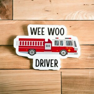 May include: White sticker with a red fire truck and the words "WEE WOO DRIVER" in black text.