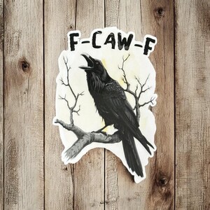 May include: A sticker featuring a black raven perched on a branch with bare twigs. The raven is depicted with its beak open, as if cawing. The text "F-CAW-F" is above the raven, set against a light yellow background.