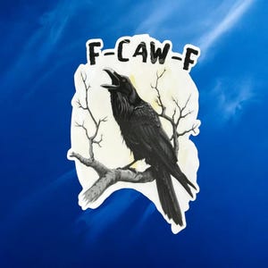 May include: A sticker featuring a black raven perched on a branch, with the text "F-CAW-F" above. The raven is set against a light background with bare tree branches, all against a blue sky.
