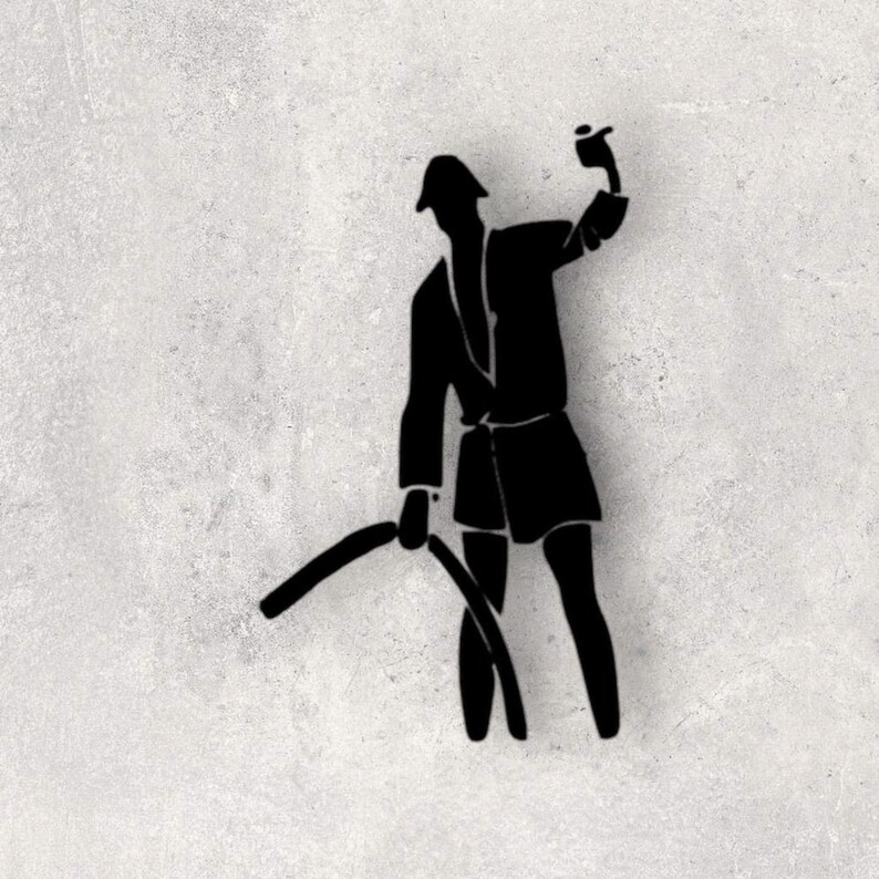 May include: A black silhouette wall decal depicting a figure wearing a hat and jacket, holding a raised object in one hand and a curved, elongated object extending downward in the other hand, creating a distinct graphic shape against the surface.