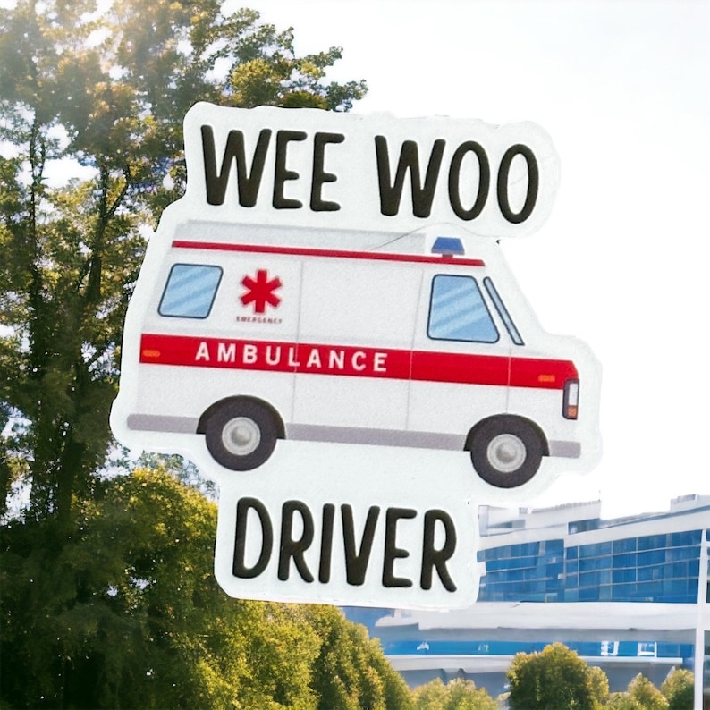 Op de afbeelding: Een witte ambulance met een rode streep en het woord "AMBULANCE" erop gedrukt. De ambulance heeft een rode ster op de zijkant en een blauw zwaailicht op het dak. De woorden "WEE WOO DRIVER" staan boven en onder de ambulance.