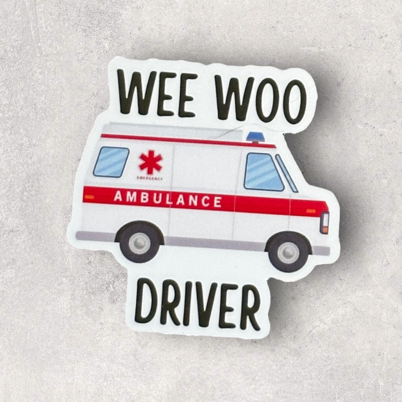 Op de afbeelding: Witte ambulance sticker met rode accenten en de woorden "WEE WOO DRIVER" in zwart. De ambulance heeft een rood kruis en het woord "AMBULANCE" aan de zijkant.