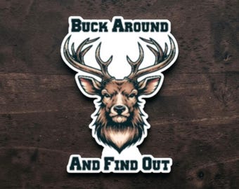 May include: A die-cut sticker featuring a brown deer head with large antlers. The text BUCK AROUND is printed in dark blue above the deer, and the text AND FIND OUT is printed in dark blue below the deer, all on a white background.