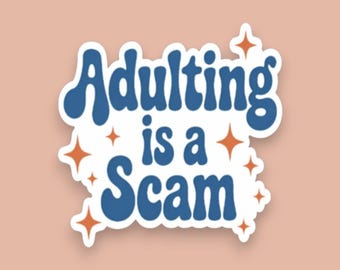 May include: A die-cut sticker featuring the blue text Adulting is a Scam in a bold, wavy font. The design is accented with several small, four-pointed orange stars scattered around the lettering, all set against a plain, light peach background.