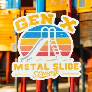 Op de afbeelding: Een sticker met een retro-ontwerp met een glijbaan en de tekst "GEN X METAL SLIDE STRONG". Het ontwerp bevat een kleurrijke zonsondergang met blauwe, gele, oranje en rode strepen, en een witte glijbaan en ladder.