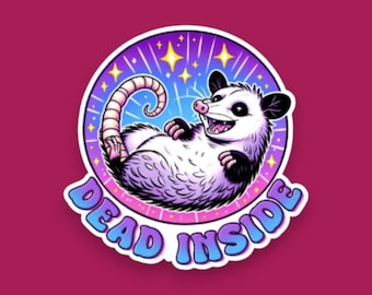 May include: A circular sticker featuring a white and grey opossum lying on its back with a pink nose and black ears. The background is a purple and blue gradient with yellow stars. The text DEAD INSIDE is printed in blue at the bottom.