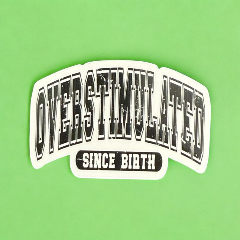 May include: A white sticker with the words "OVERSTIMULATED" in a bold, black, distressed font, arched across the top. Below, in a smaller, black font, it reads "SINCE BIRTH". The sticker is set against a bright green background.
