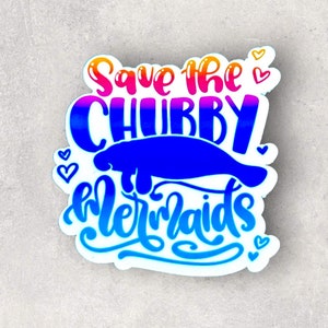 Peut inclure: Un autocollant color&eacute; avec le texte "Save the Chubby Mermaids" dans un d&eacute;grad&eacute; arc-en-ciel. Une silhouette de lamantin bleue est repr&eacute;sent&eacute;e au centre de l'autocollant.
