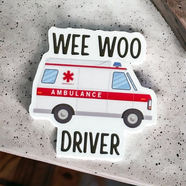 Op de afbeelding: Witte sticker met een cartoon ambulance en de tekst "WEE WOO DRIVER".