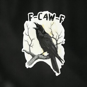 May include: A black raven perched on a branch, with the text "F-CAW-F" above it. The raven is set against a light yellow background with bare tree branches, all on a black background.