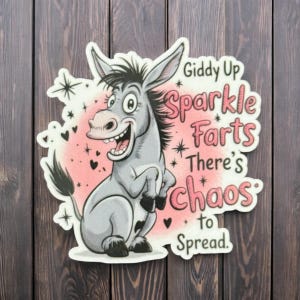 May include: A sticker featuring a cartoon donkey with a smiling expression. The donkey is gray with black accents and is set against a pink background with hearts and stars. Text reads "Giddy Up Sparkle Farts There's Chaos to Spread."