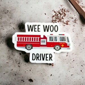 May include: A white sticker with a red fire truck and the text "WEE WOO DRIVER". The fire truck has a ladder, a yellow star, and the words "FIRE DEPT."