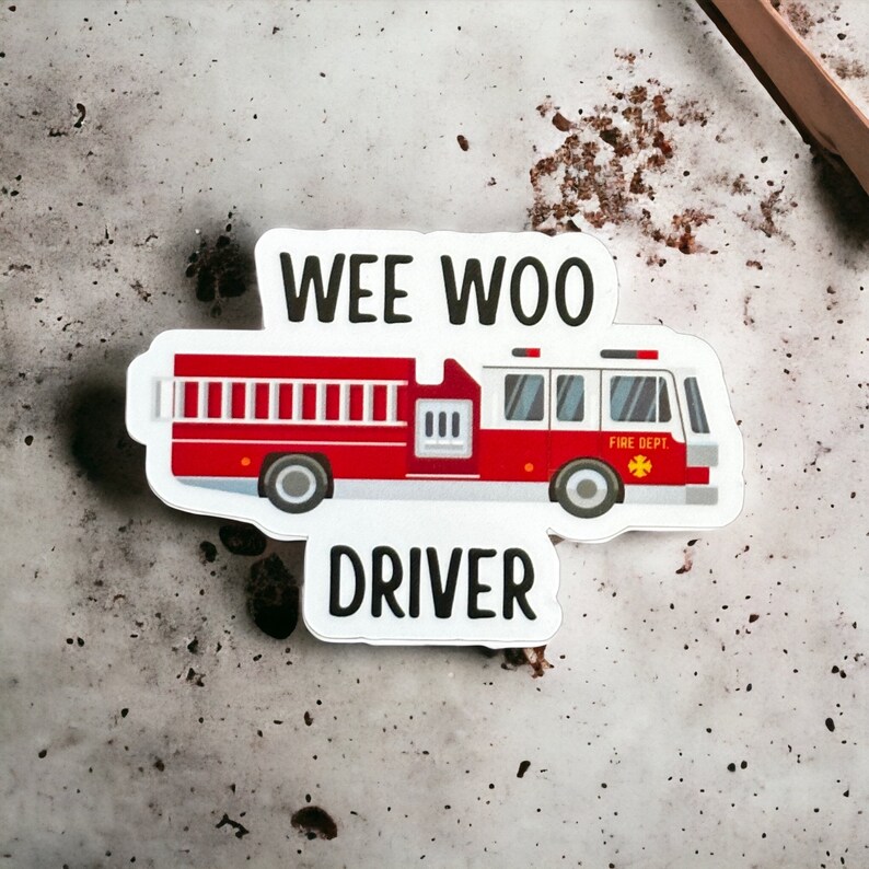 May include: A white sticker with a red fire truck and the text "WEE WOO DRIVER". The fire truck has a ladder, a yellow star, and the words "FIRE DEPT."