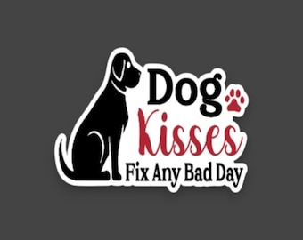 May include: A die-cut sticker featuring a black silhouette of a sitting dog next to the text Dog Kisses in black and red script, followed by the black text Fix Any Bad Day and a small red paw print icon on a white background with a thin border.