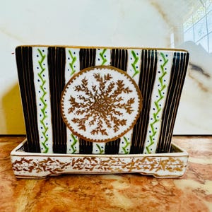 May include: Rectangular ceramic planter with a matching tray. The planter features vertical black and gold stripes, green and blue accents, and a central gold snowflake design. The tray and rim have gold floral patterns.