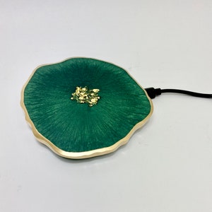 May include: A green wireless charging pad with a gold rim and gold flecks in the center. The charging pad is shaped like a flower.
