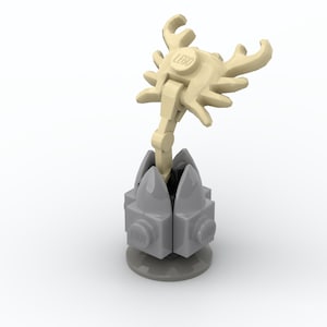 May include: A Lego sculpture featuring a light tan, antler-like structure with the word "LEGO" on top. The structure is supported by a gray base with a series of gray, pointed elements. The sculpture is set against a white background.