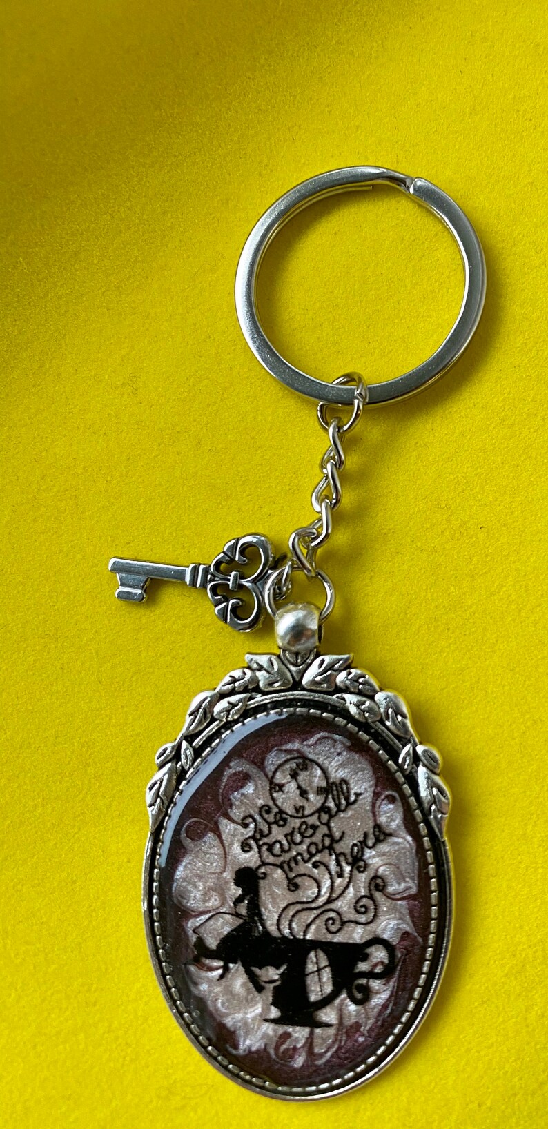 Alice in Wonderland swirling resin design with character inclusion in a Silver Bezel with key charm on Keychain