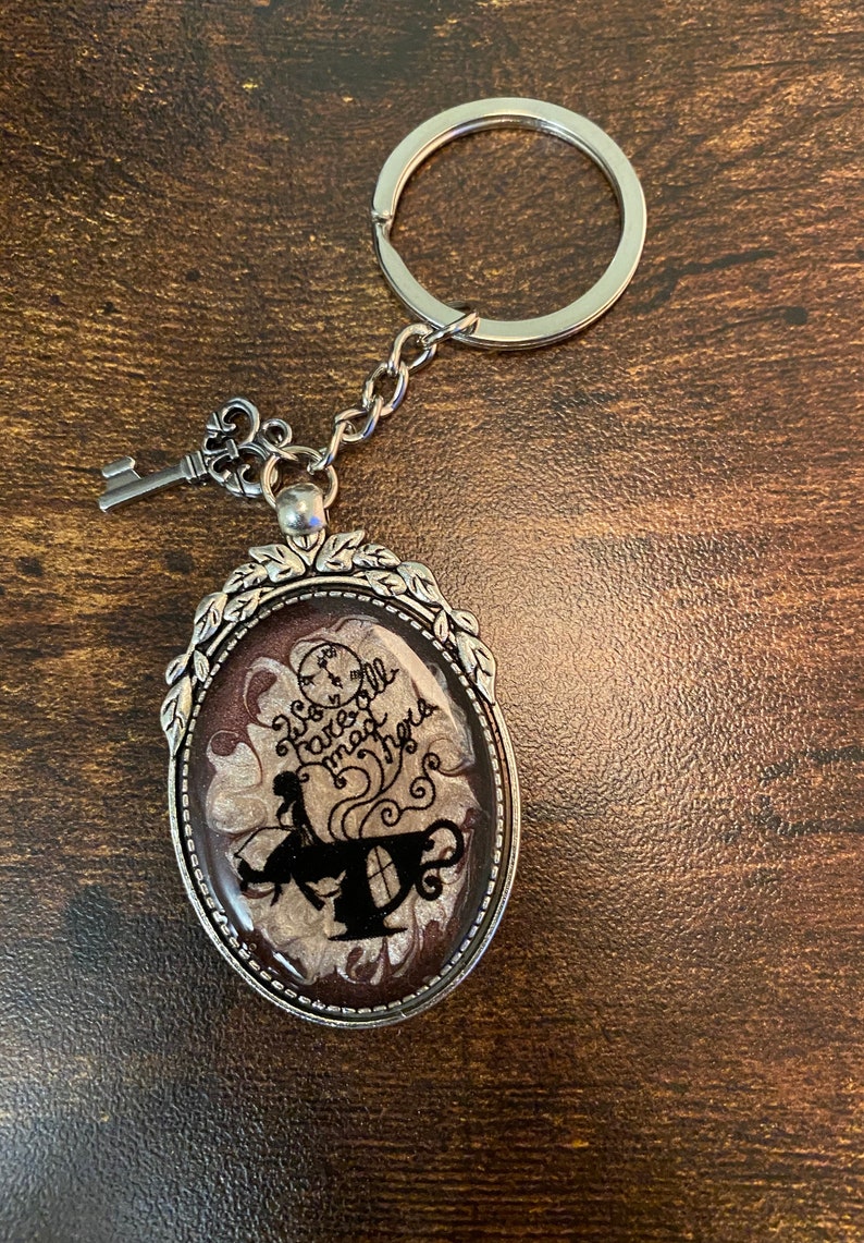 Alice in Wonderland swirling resin design with character inclusion in a Silver Bezel with key charm on Keychain