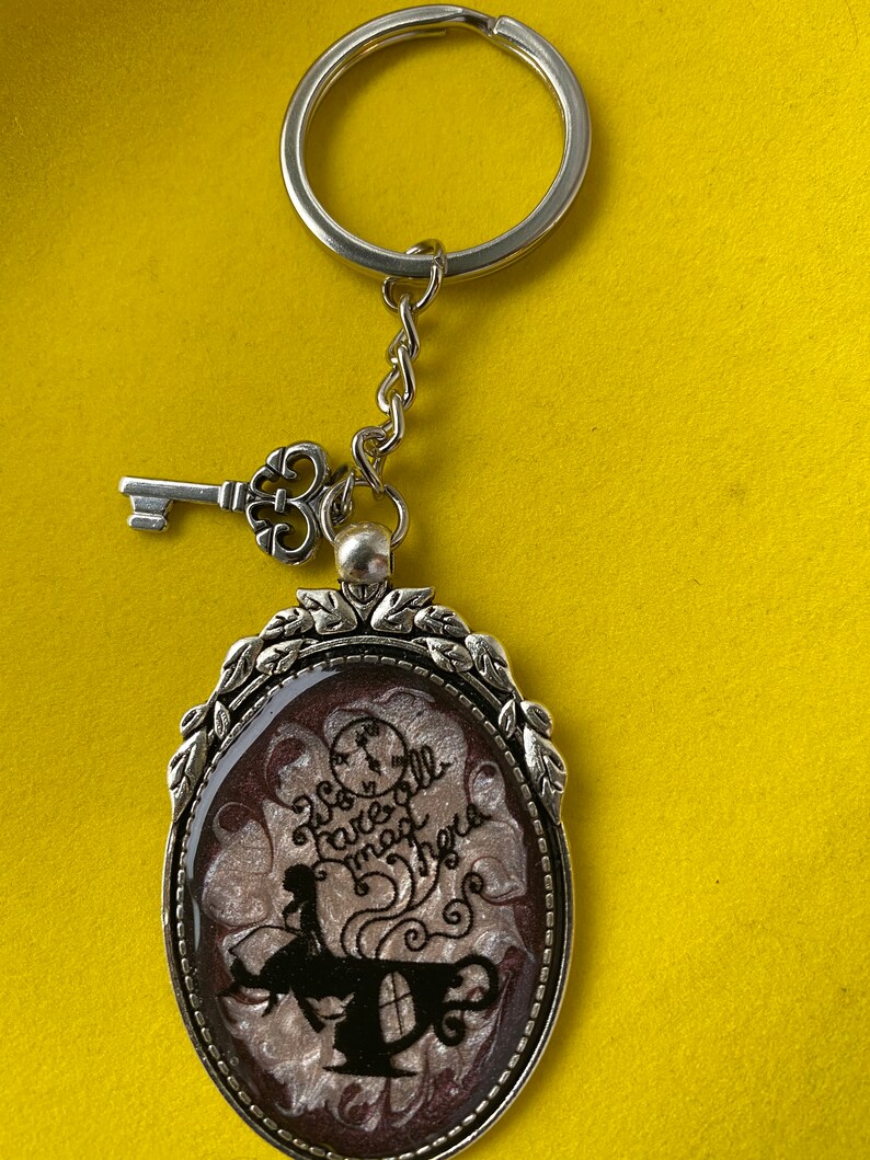 Alice in Wonderland swirling resin design with character inclusion in a Silver Bezel with key charm on Keychain