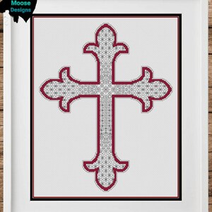 Könnte beinhalten: Ein gerahmtes Kreuzstichdesign mit einem detaillierten Kreuz mit burgunderfarbener Umrandung und komplizierten weißen und schwarzen Mustern. Das Kreuz ist auf einem weißen Hintergrund zentriert, eingerahmt in einem weißen Rahmen mit einem schwarzen Innenrand. Das Kunstwerk wird in einem weißen Rahmen präsentiert.