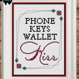 May include: Cross-stitch pattern with a white background and red, green, and pink embroidery. The pattern says "Phone Keys Wallet" with a stylized "Kiss" underneath.