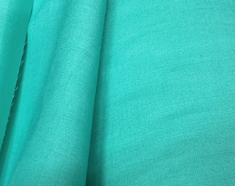 May include: A close-up of a smooth, teal fabric. The fabric is folded in half, showing the texture and color.