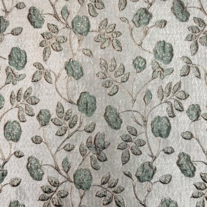 May include: A silver fabric with a repeating pattern of green roses and leaves.