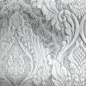 May include: Close-up of a detailed, textured fabric with a repeating floral pattern in shades of white and gray. The design features ornate, raised elements and a vintage aesthetic, suitable for upholstery or decorative projects.