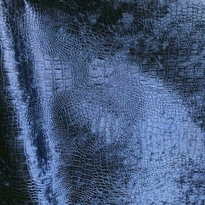 May include: Blue fabric with a crocodile skin pattern. The fabric has a slightly textured surface.