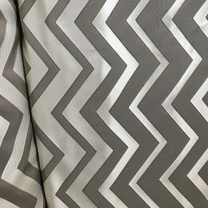 May include: White and gray chevron patterned fabric. The fabric has a subtle sheen and a smooth texture.