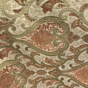May include: A close-up of a fabric with a paisley pattern in shades of beige, brown, and gold. The fabric has a textured, woven look.