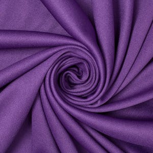 May include: A close-up shot of a swirl of purple fabric. The fabric is a solid color, with a subtle texture visible. The folds create a spiral pattern, with the center of the swirl appearing darker than the outer edges.