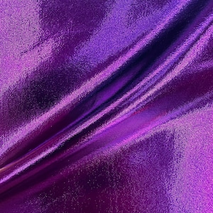 May include: Close-up of a purple iridescent fabric with a smooth, silky texture. The fabric is folded in a diagonal pattern, creating a soft, flowing look.