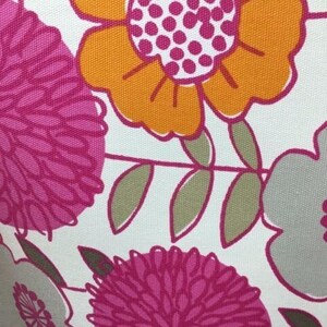 May include: White fabric with a floral pattern featuring pink, orange, and gray flowers. The flowers are stylized and have a retro look.