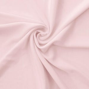 May include: A close-up shot of a light pink fabric with soft folds and a swirling pattern. The fabric appears smooth and has a subtle sheen, creating a delicate and elegant aesthetic. The overall texture suggests a lightweight material.