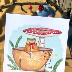 Petite grenouille mignonne dans sa coquille de noix sous son champignon jolie carte peinte à l'aquarelle et reproduite sur du papier épais de très bonne qualité