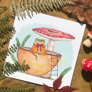 Petite grenouille mignonne dans sa coquille de noix sous son champignon jolie carte peinte à l'aquarelle et reproduite sur du papier épais de très bonne qualité
