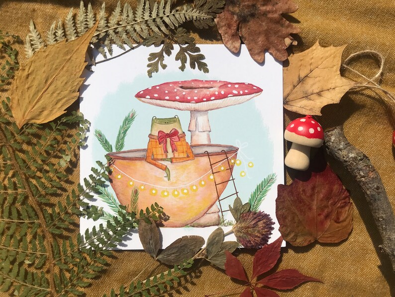 Petite grenouille mignonne dans sa coquille de noix sous son champignon jolie carte peinte à l'aquarelle et reproduite sur du papier épais de très bonne qualité