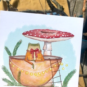 Petite grenouille mignonne dans sa coquille de noix sous son champignon jolie carte peinte à l'aquarelle et reproduite sur du papier épais de très bonne qualité