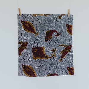 May include: A white fabric with a black and white swirl pattern and red and yellow fish designs.