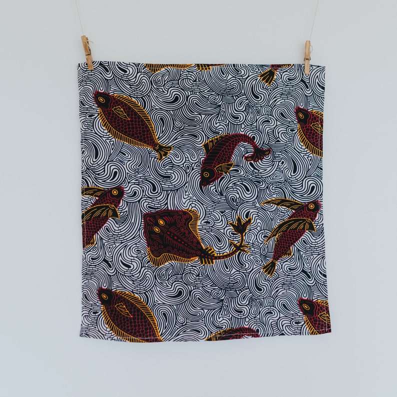 May include: A white fabric with a black and white swirl pattern and red and yellow fish designs.