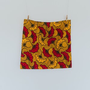 May include: A yellow and red fabric with a floral pattern. The fabric has a black outline around the flowers.
