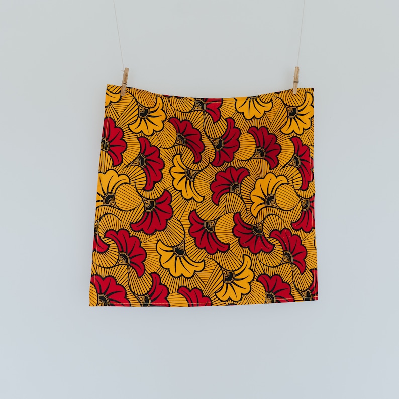 May include: A yellow and red fabric with a floral pattern. The fabric has a black outline around the flowers.